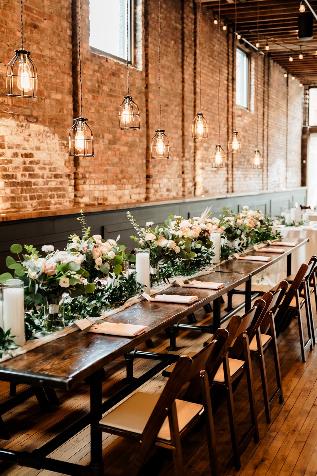 Banquet-style wedding head table with floral garland and candles at Mercantile Hall