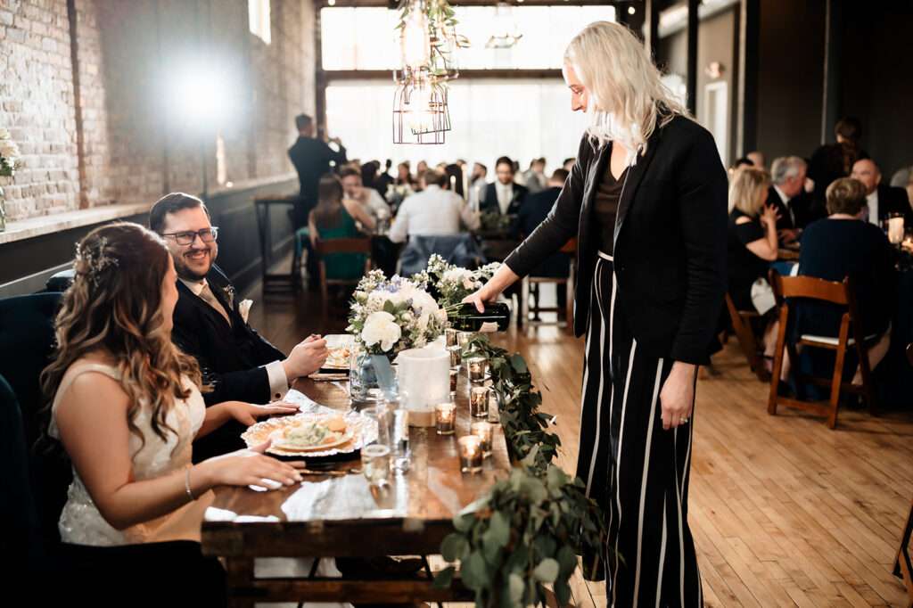 Racheal pouring champagne for newlyweds