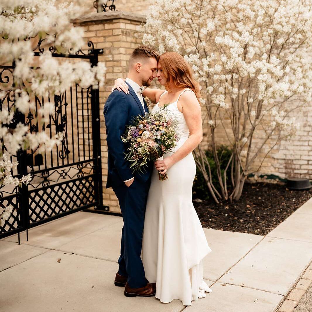 Newlyweds pose in front of The Urb Garden gates in spring.