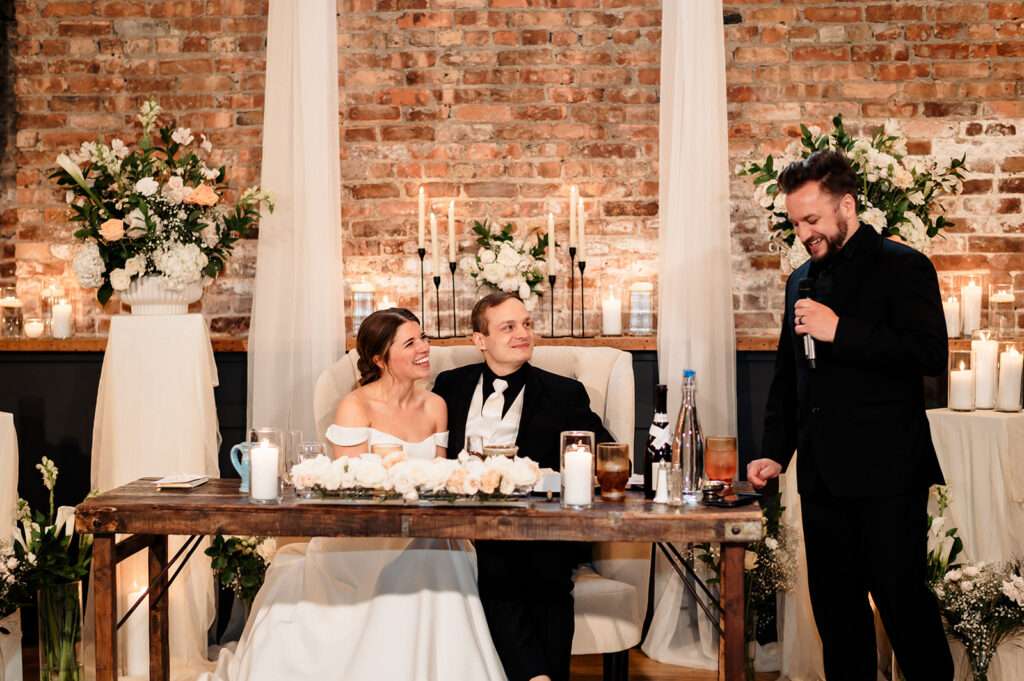 Newlyweds listen to a speech during their wedding reception at Mercantile Hall.