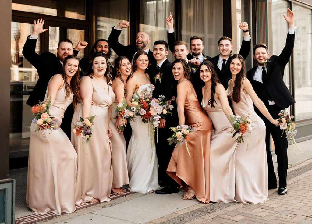 Newlyweds pose in front of Mercantile Hall with their wedding party