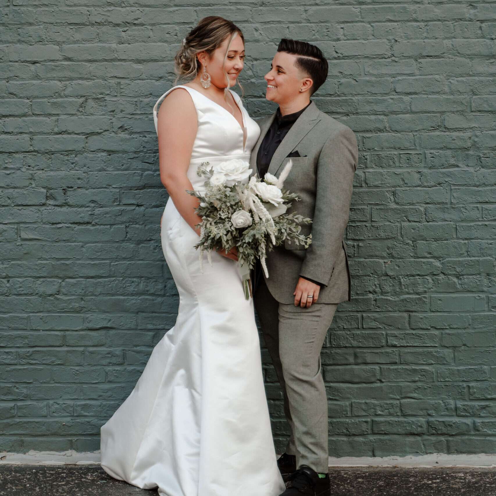 Newlyweds pose in front of the green wall at Mercantile Hall.