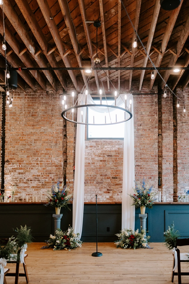 Indoor wedding ceremony setup with floral arrangements and draped fabric at Mercantile Hall