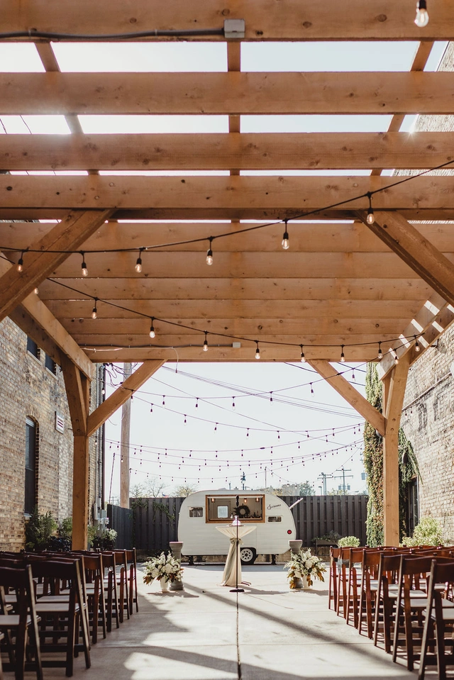 Outdoor ceremony setup under wooden pergola with camper bar at Mercantile Hall in Burlington, WI