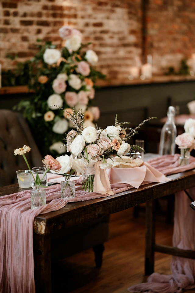 Romantic sweetheart table with blush floral arrangements and mauve runner at Mercantile Hall