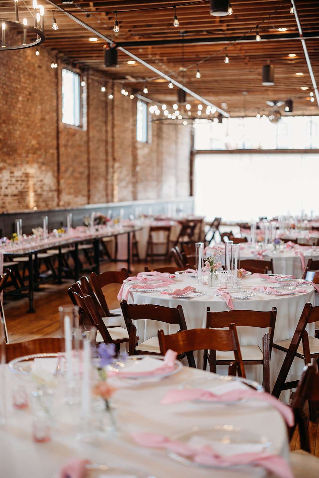 Mercantile Hall wedding reception setup with round tables, pink napkins, and exposed brick walls
