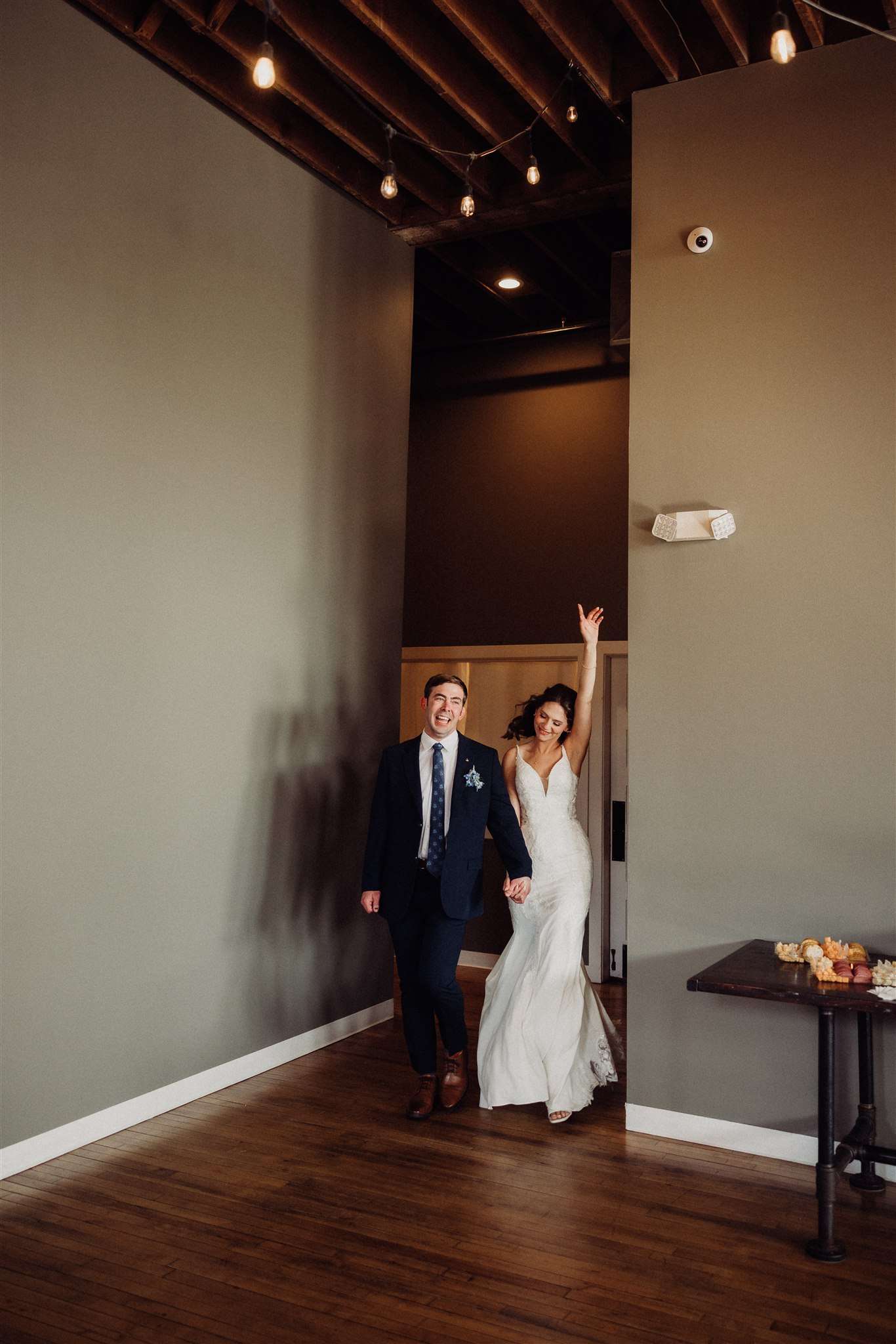 Bride and groom enter their reception hand in hand, full of smiles and celebration.