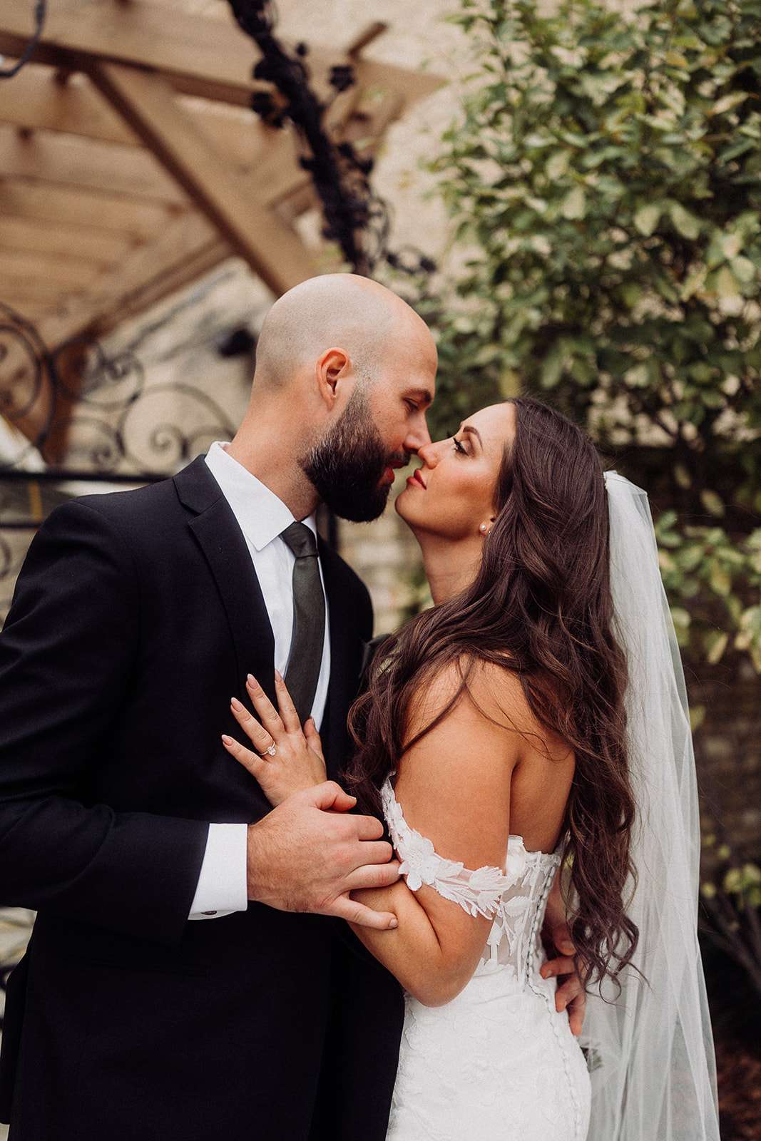 Bride and groom lean in for a romantic kiss under the pergola at Mercantile Hall