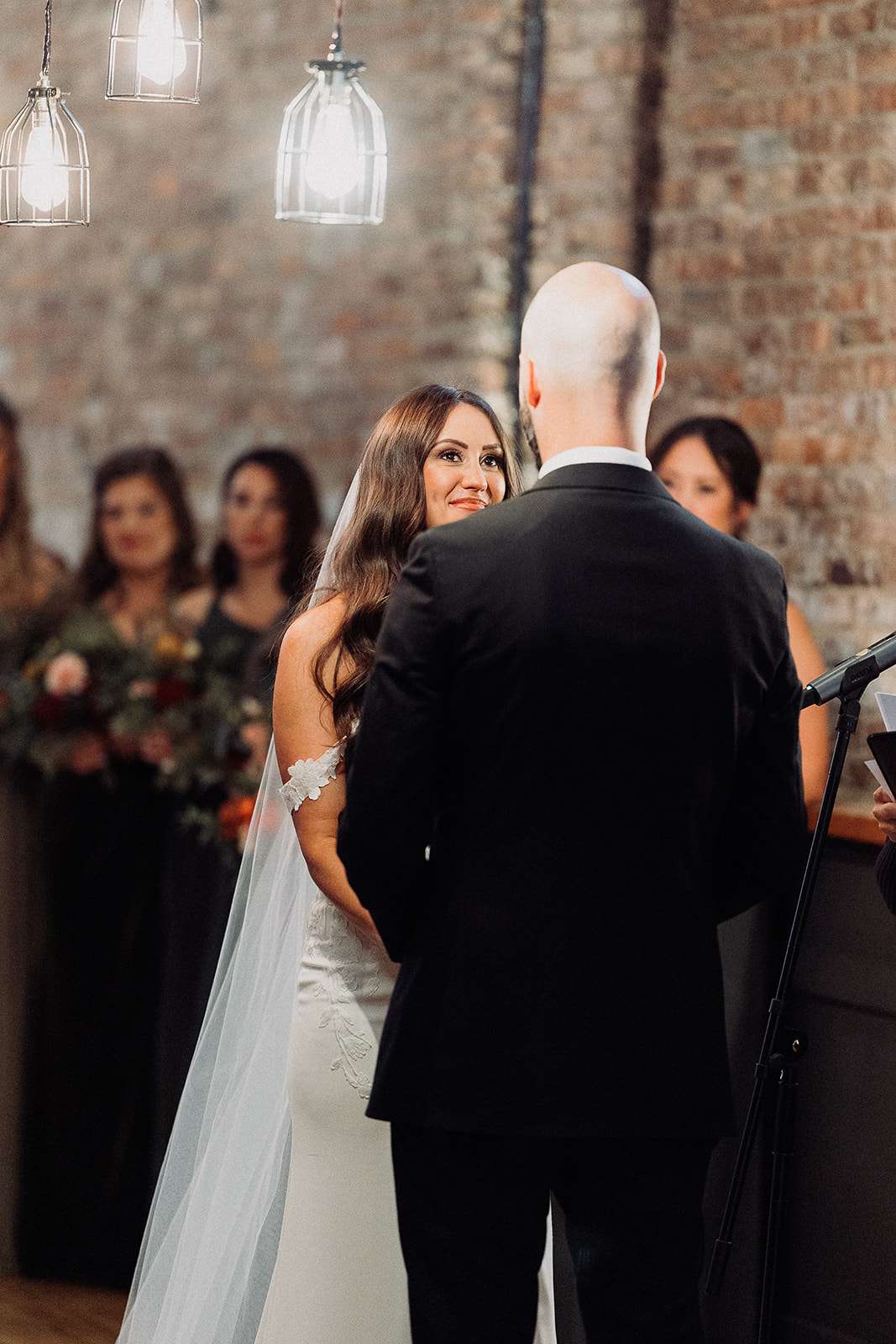 Bride and groom exchange vows in an indoor ceremony under soft lighting at Mercantile Hall