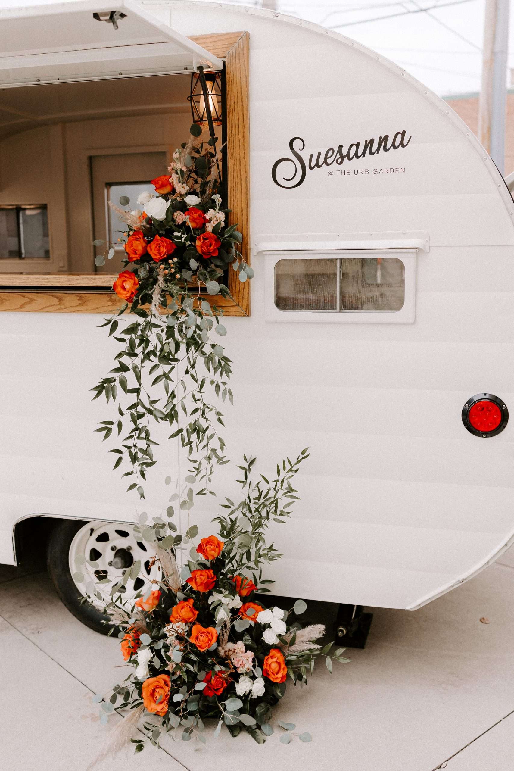 Suesanna camper bar decorated with cascading floral arrangements of red and orange roses at Mercantile Hall's Urb Garden