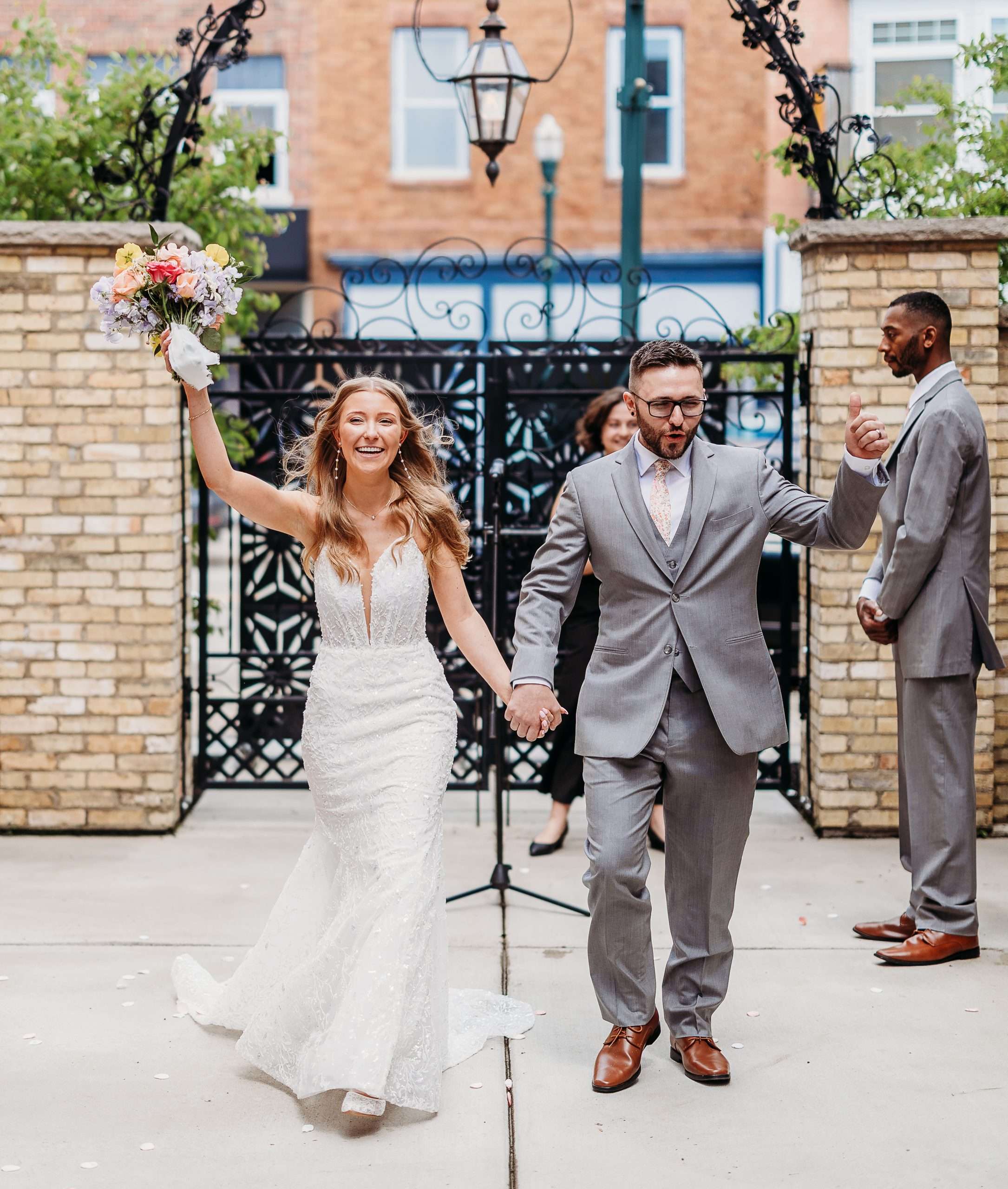Joyful bride and groom exiting outdoor wedding ceremony at Mercantile Hall in Burlington, WI