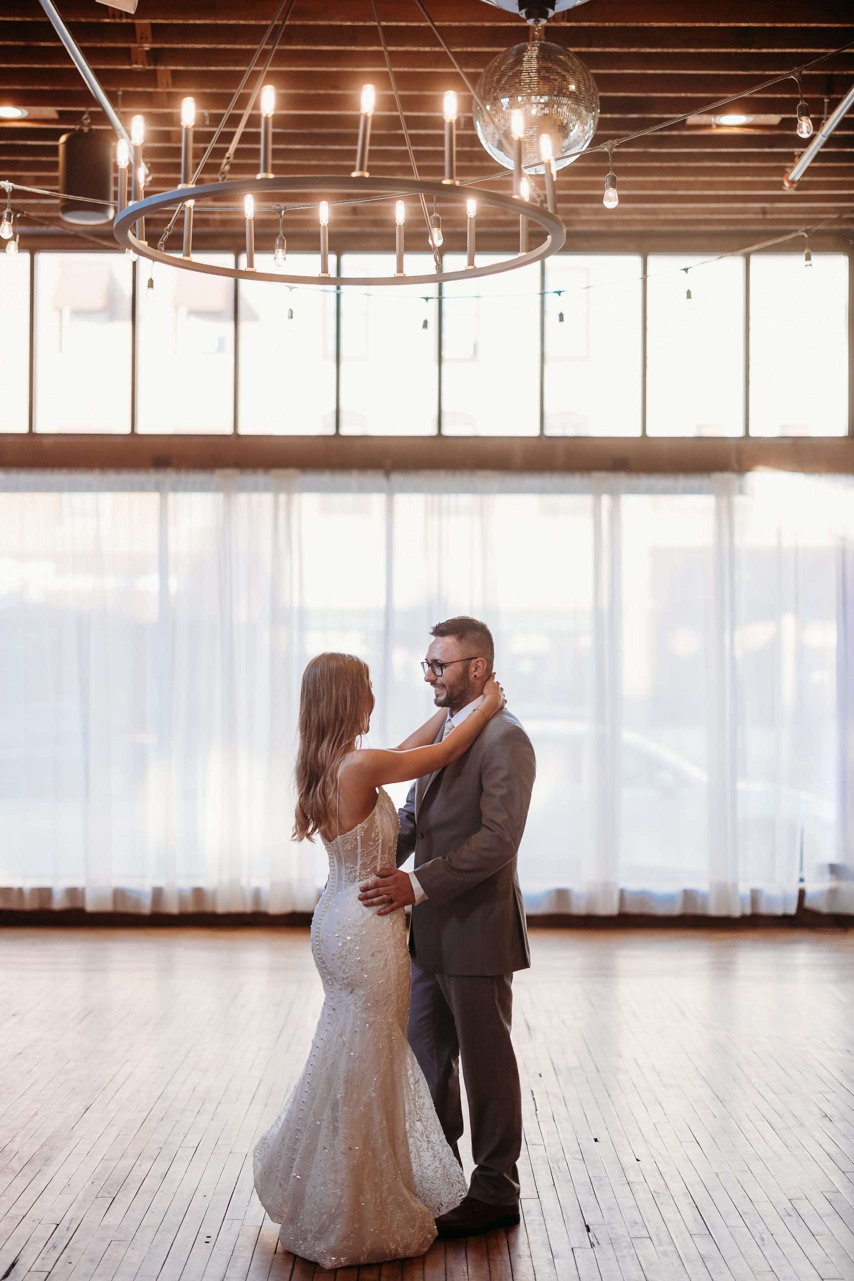 Bride and groom sharing intimate first dance in bright airy reception hall with wooden floors and large windows at Mercantile Hall