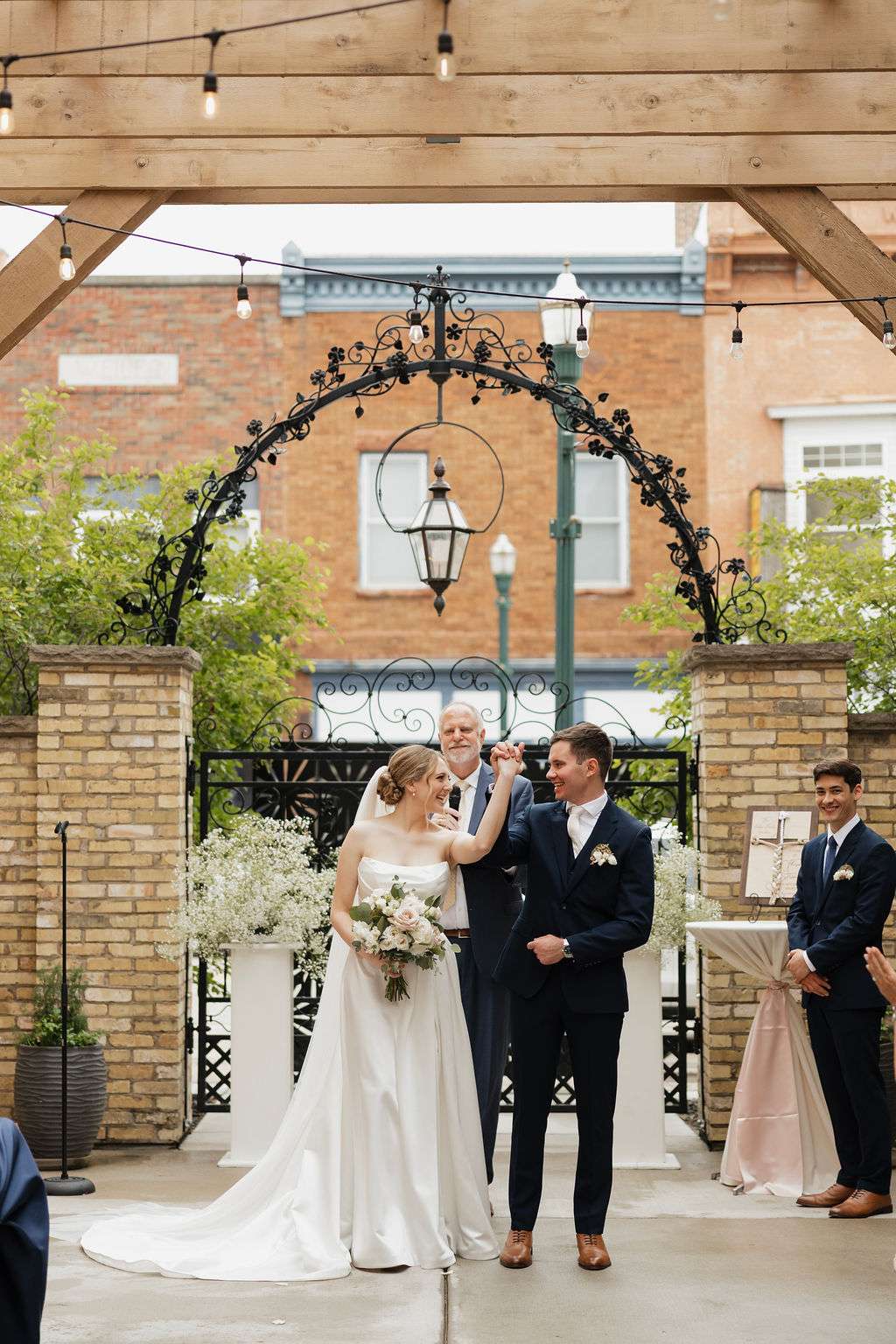 Bride and groom sharing a joyful moment during outdoor wedding ceremony under arched pergola at Mercantile Hall
