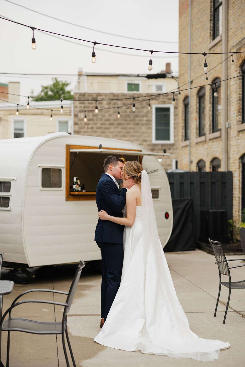 Bride and groom share a quiet moment near a vintage white camper bar at Mercantile Hall