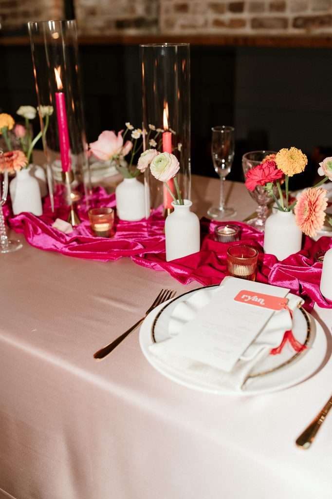 Wedding reception table with pink velvet runner, candlelight, and spring florals at Mercantile Hall in Burlington, WI