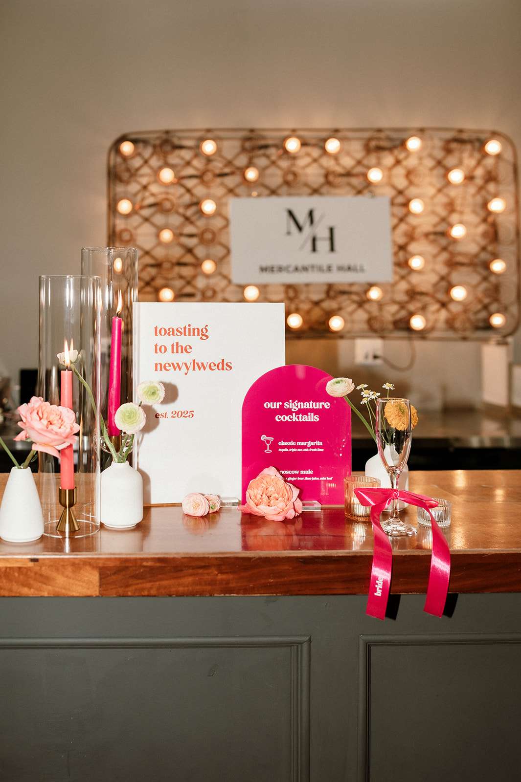 Modern wedding cocktail display with signature drinks, pink florals, and Mercantile Hall signage in Burlington, Wisconsin