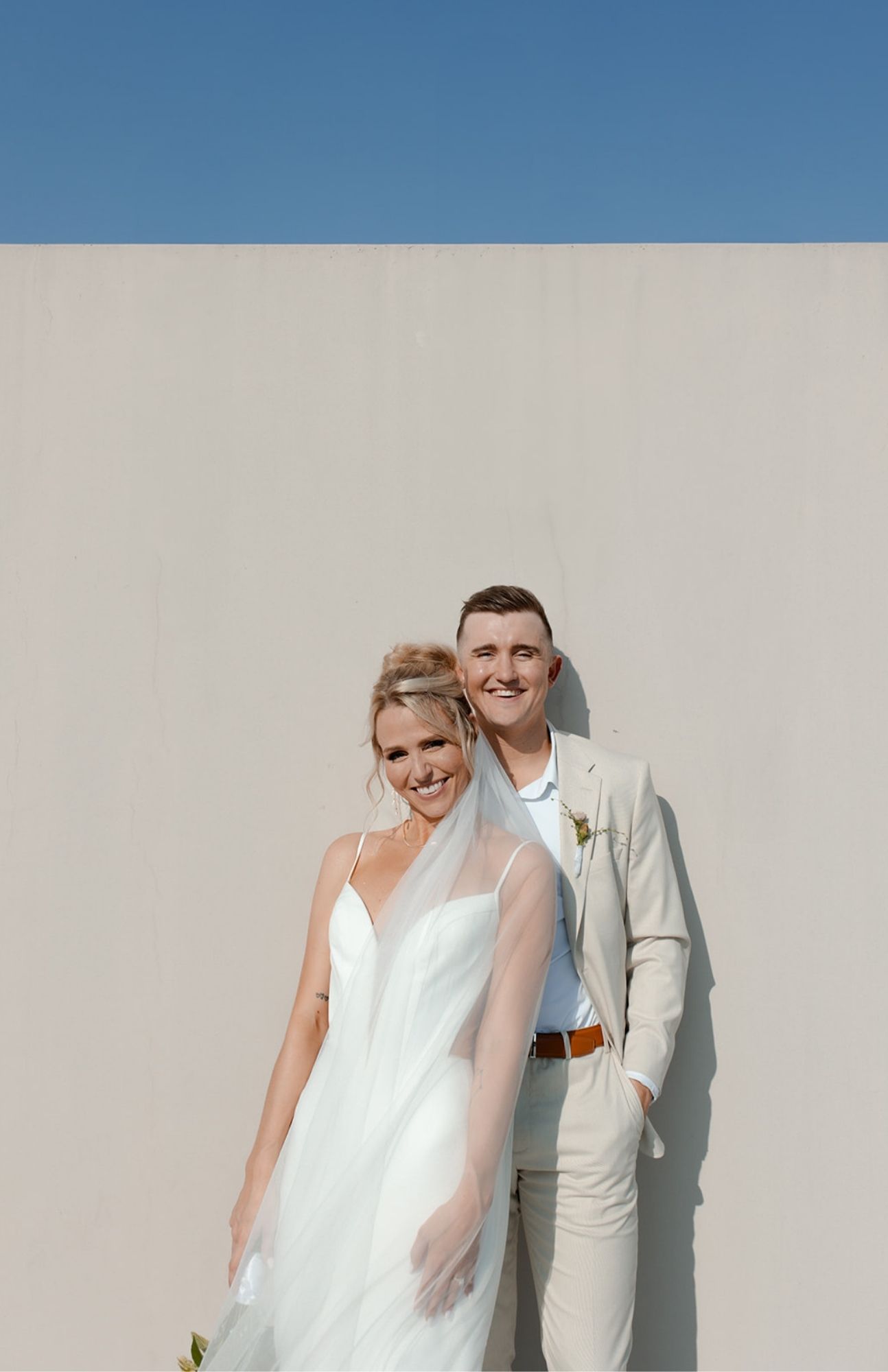 Bride resting her head on her partner’s shoulder as they walk through a side street in downtown Burlington, Wisconsin, after their wedding.