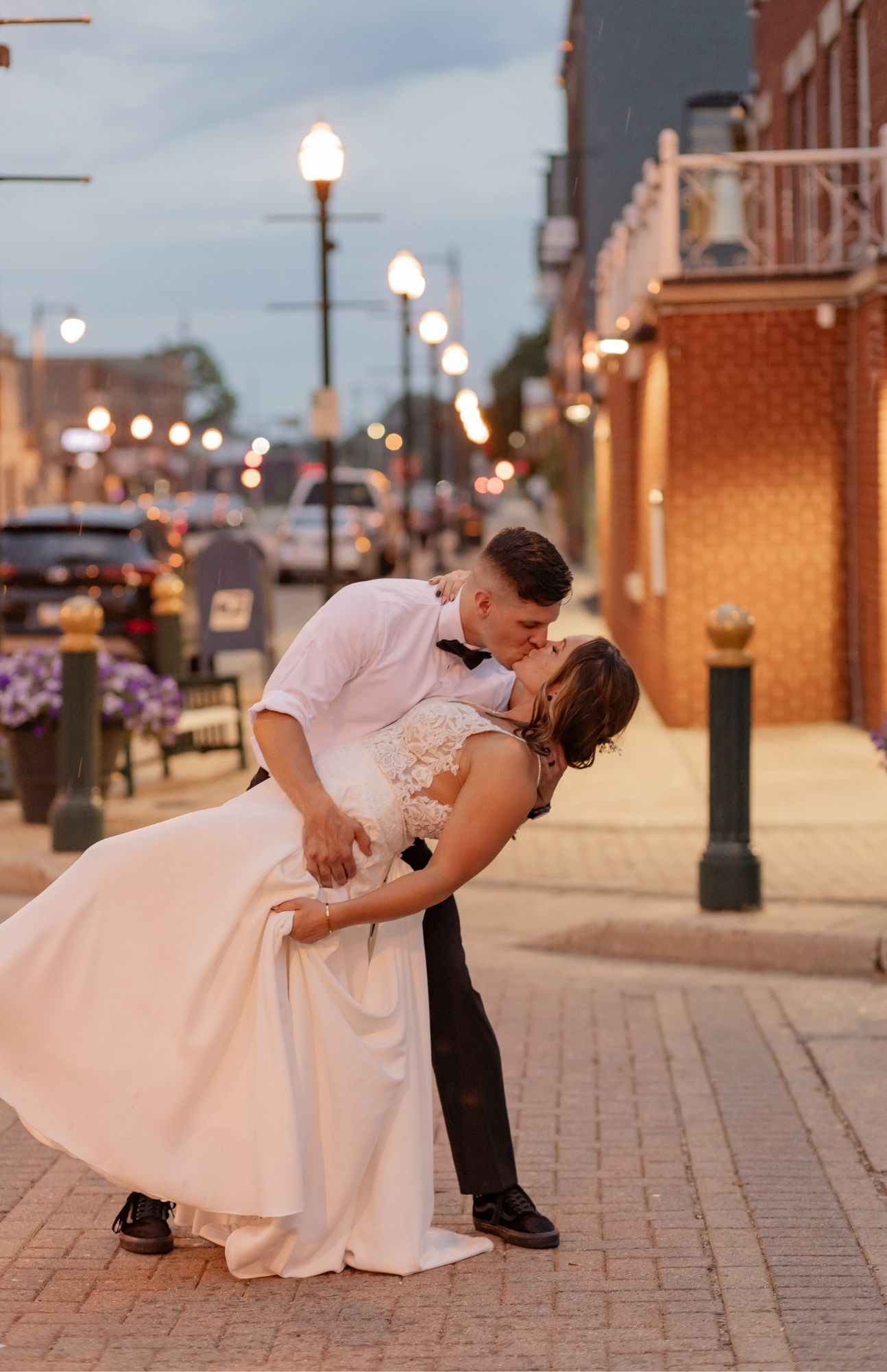 Wedding couple walking hand in hand down a brick-lined street in downtown Burlington, Wisconsin, sharing a quiet, romantic moment after their ceremony.